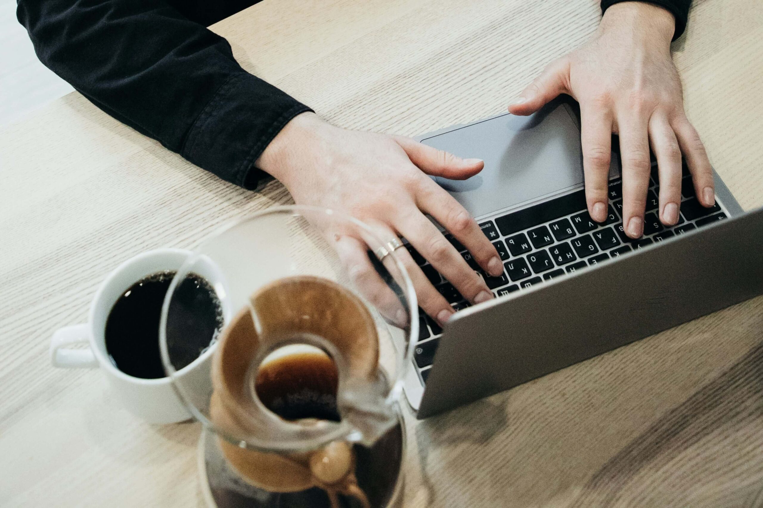 a person using a laptop on a wooden table
