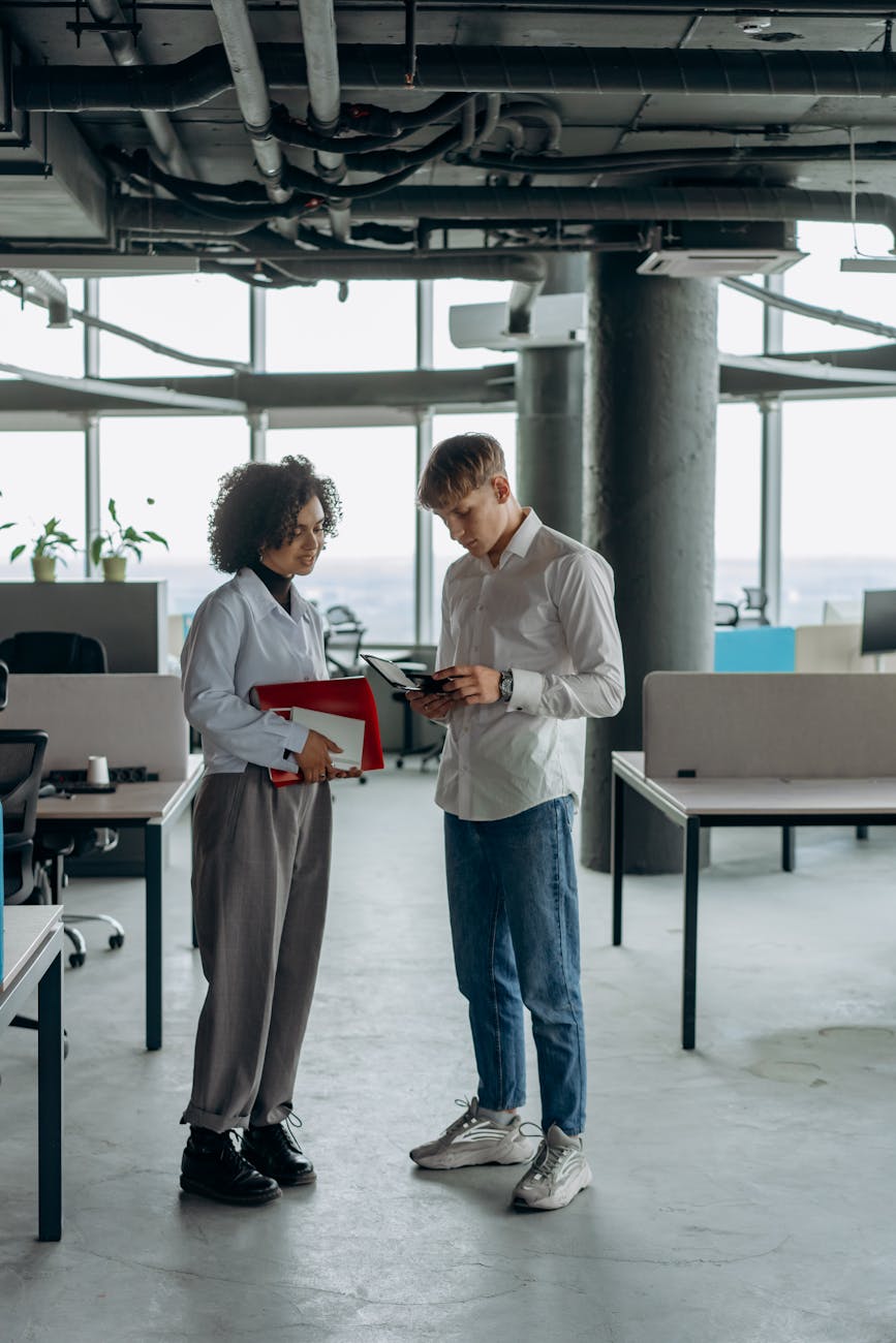 colleagues standing in white long sleeve shirts calculating financial report using a calculator