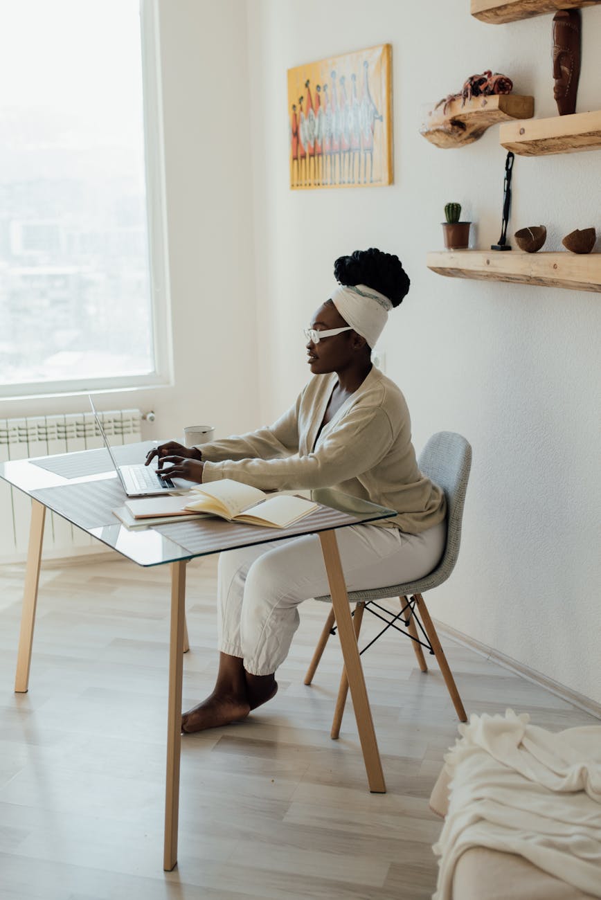 a woman using a laptop while sitting at the glass table