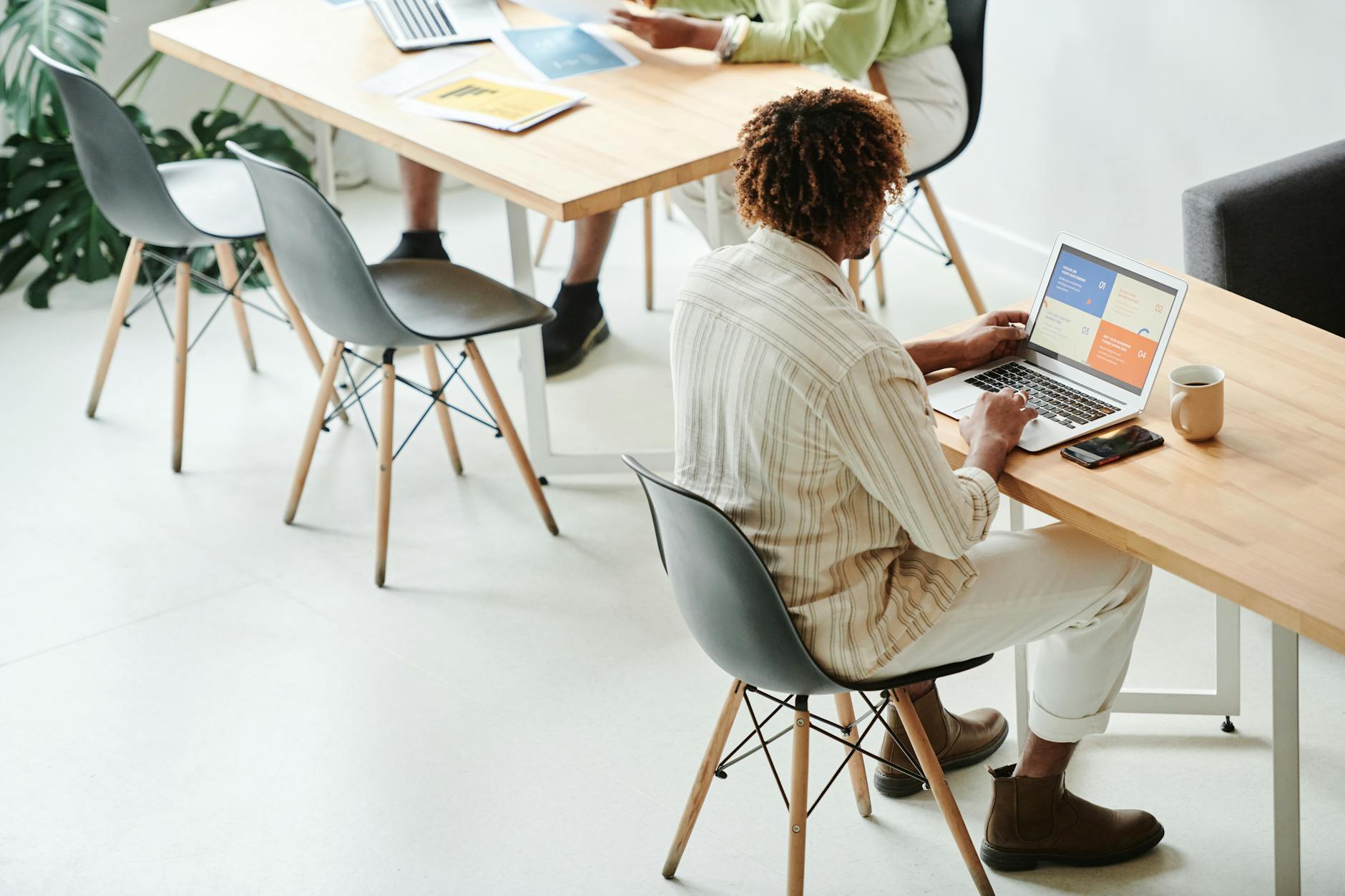 man in striped long sleeve shirt sitting on table using laptop