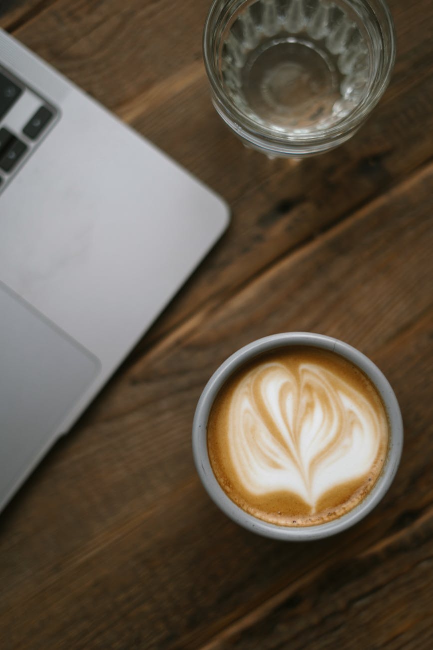 close up shot of a cup of cappuccino coffee on wooden surface