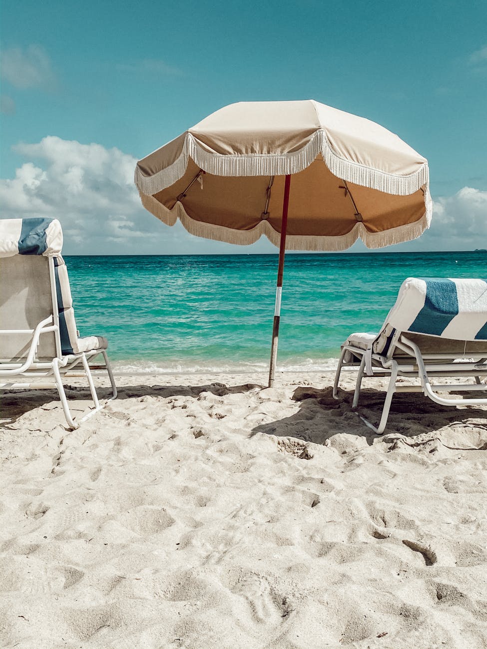 chairs and an umbrella on a beach with a beautiful view of the ocean
