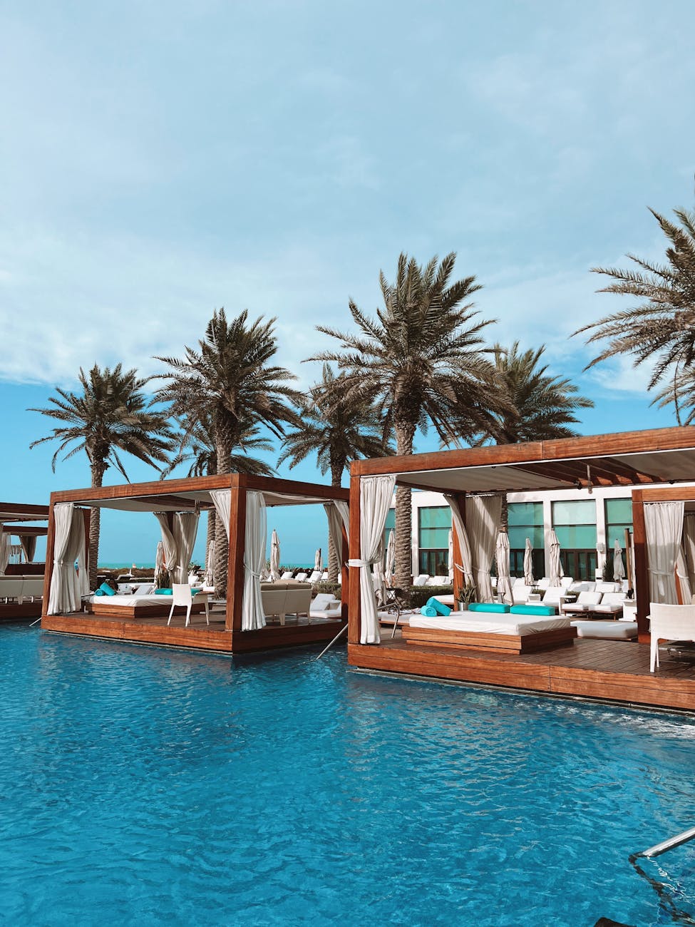 wooden loungers with mattresses over swimming pool in saadiyat beach club