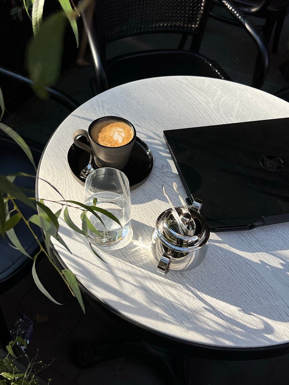 cup of coffee glass of water and a laptop on a table in a cafe